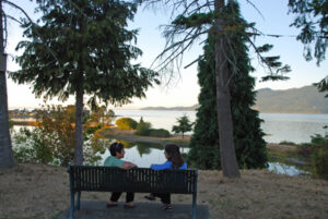 Two people facing each other as they sti on a bench overlooking the Salish Sea at samish island campground