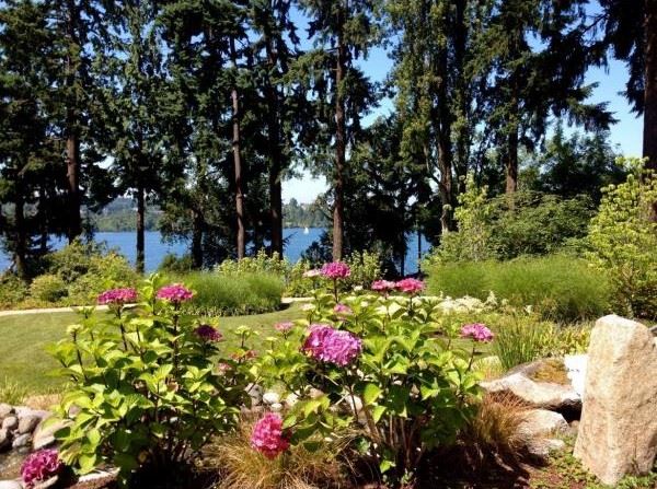 a bed of pink flowers in front of a view of lake washington, on the grounds of the Peace and Spirituality Center at St. Mary's.