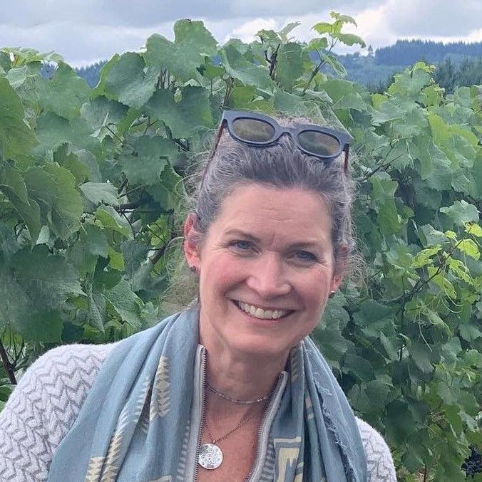 Photo of instructor Annie Shull, smiling in front of some vines.