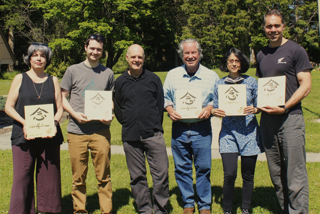 Tim Burnett posing with five of the MTTP graduates, holding calligraphy art that Tim made for them.