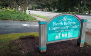 The sign outside of the North Bellevue Community Center, light blue with white lettering and a grey wooden frame.
