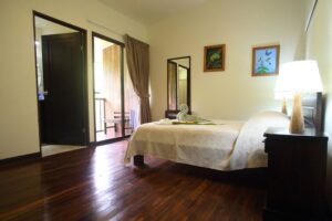 One of the bedrooms that guests may stay in while on retreat at Selva Verde Lodge. Well lit with dark wooden floors and light yellow walls, the room features a plush bed and local artwork.