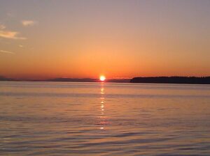 View of the orange sun setting over the calm Salish sea from Semiahmoo