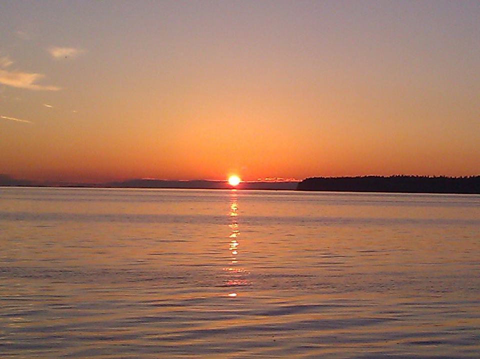 View of the orange sun setting over the calm Salish sea from Semiahmoo