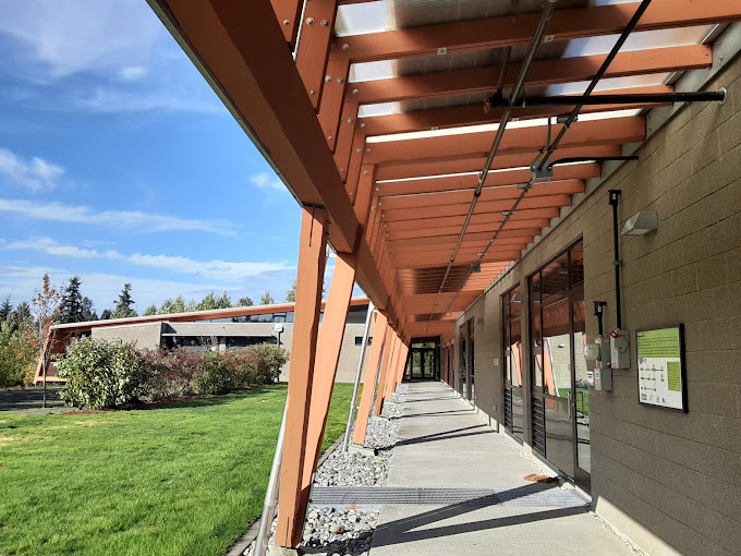 The outside of brightwater center, with exposed wooden beams against a blue sky.