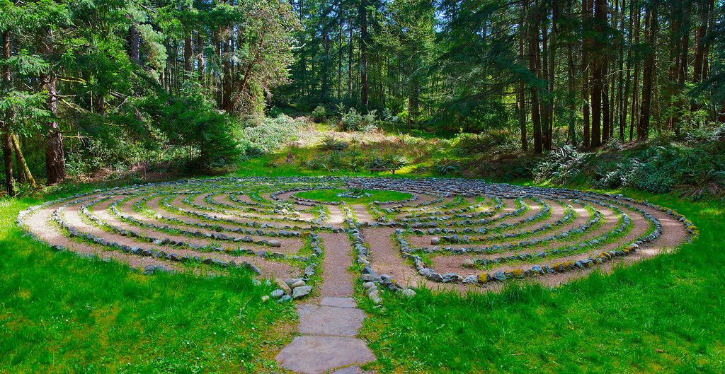 A circular labyrinth walking path made of rocks in the grass.