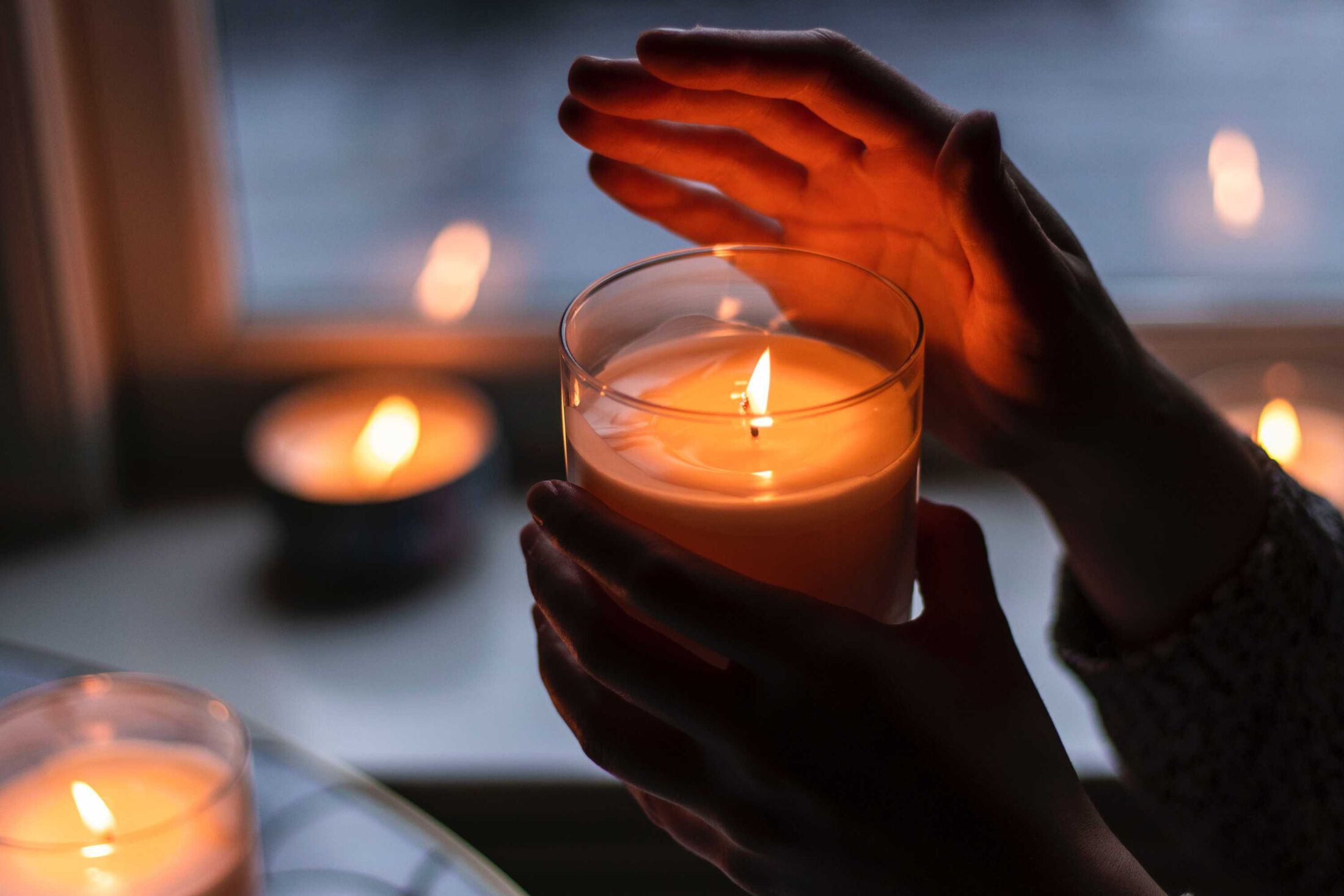 A hand hovers near a lit candle 