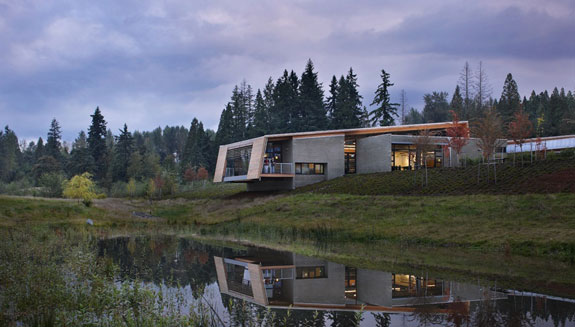 The exterior of Brightwater center, looking over a wetland area, with grey clouds and fir trees in the background. 
