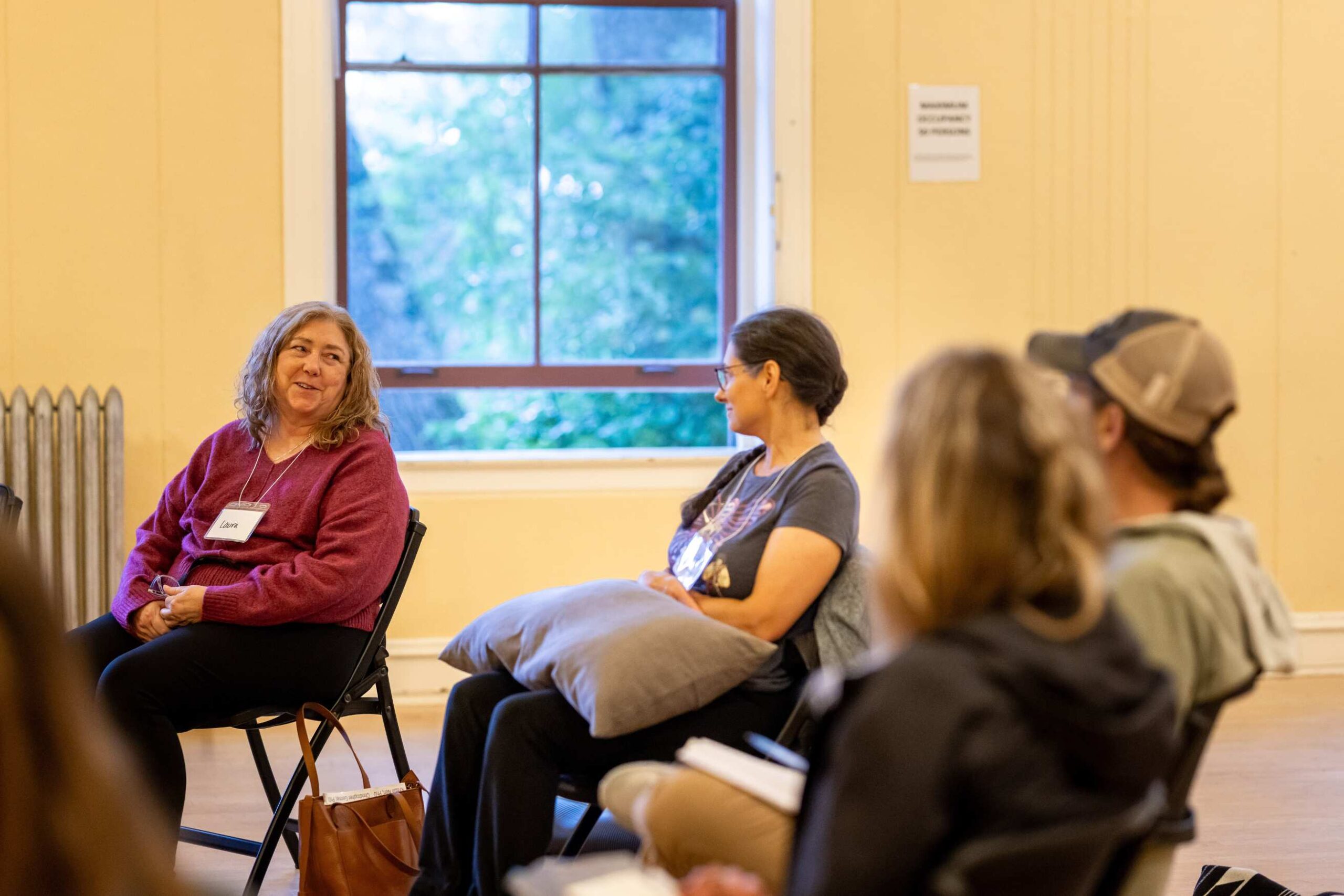 classroom participants smile and chat sitting in a circle during class