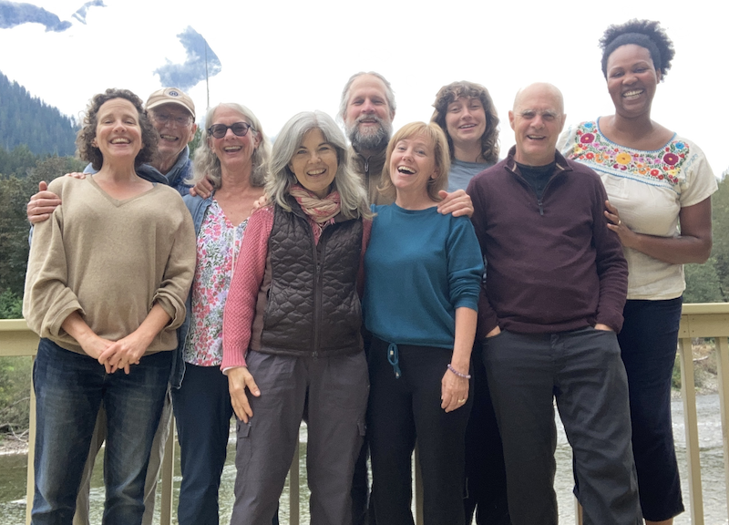 Mindfulness Northwest staff members pictured sitting on driftwood with water and sky in the background